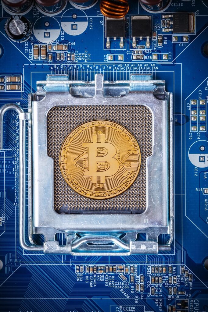 Moneda de Bitcoin colocada sobre un procesador de computadora, simbolizando la minería y el staking cripto